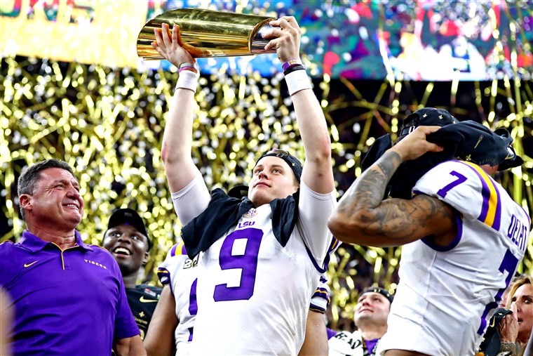 LSU coach Ed Orgeron, QB Joe Burrow, and safety Grant Delpit are presented the College Football Championship trophy as LSU defeated Clemson 42-25.