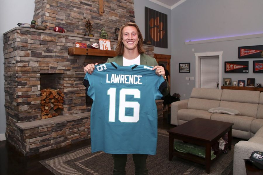 Clemson quarterback, Trevor Lawrence holds up his draft jersey after getting selected first overall by the Jacksonville Jaguars. Trevor celebrated with his family including his new wife, Marissa Mowry, and parents Jeremy and Amanda Lawrence from his home. They opted to watch the draft from his home due to Covid-19. Photo by Logan Bowles/NFL