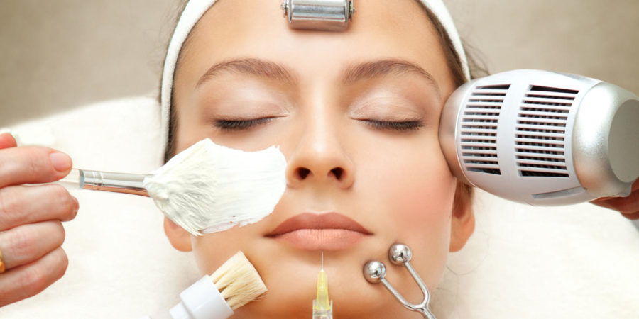 A lady relaxing at a spa with a bunch of skin care gadgets on her face.