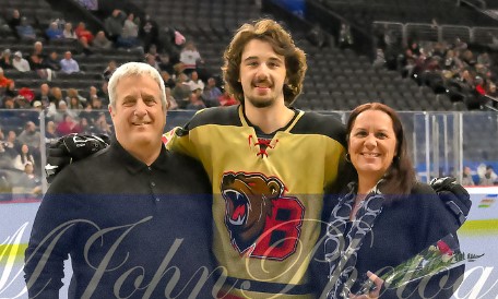 Chase and his parents standing together during one of his hockey games.