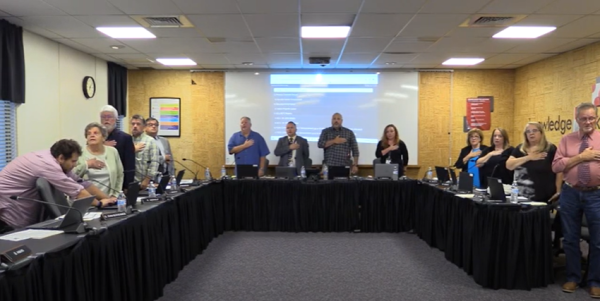 Members holding the pledge of allegiance during the beginning of the meeting.